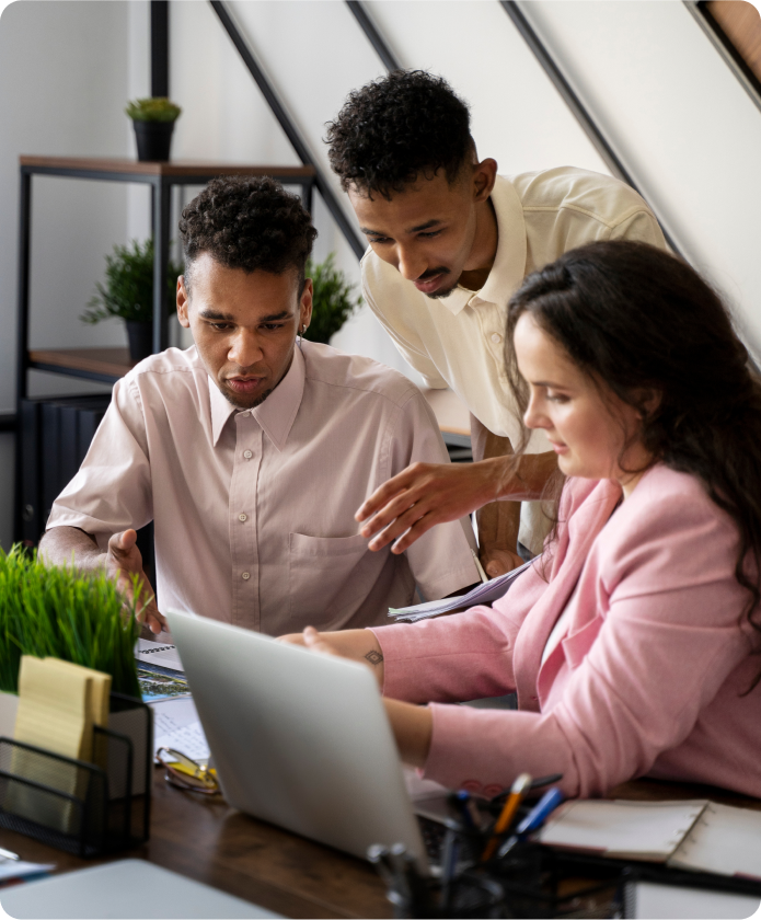 Three team members from the Clothing Team collaborate while looking at a laptop screen together