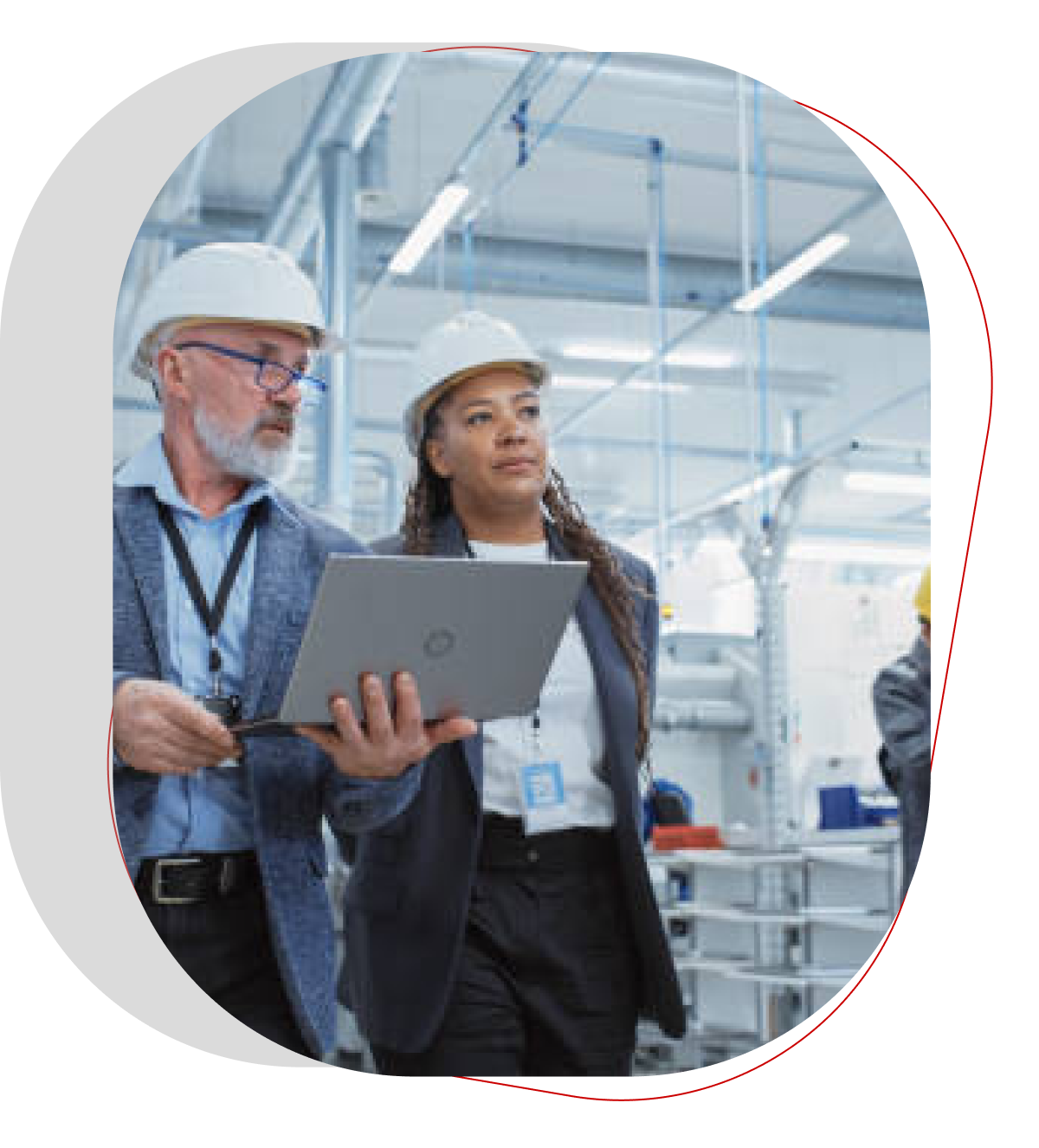 A formal, digital slide on a clean, light gray background. The slide is split into two sections by a thin, red-and-white border. The scene features a close-up of two professionals in hard hats holding and looking at a laptop in what appears to be a factory or manufacturing facility. The image conveys a professional and industrial theme related to the manufacturing sector.